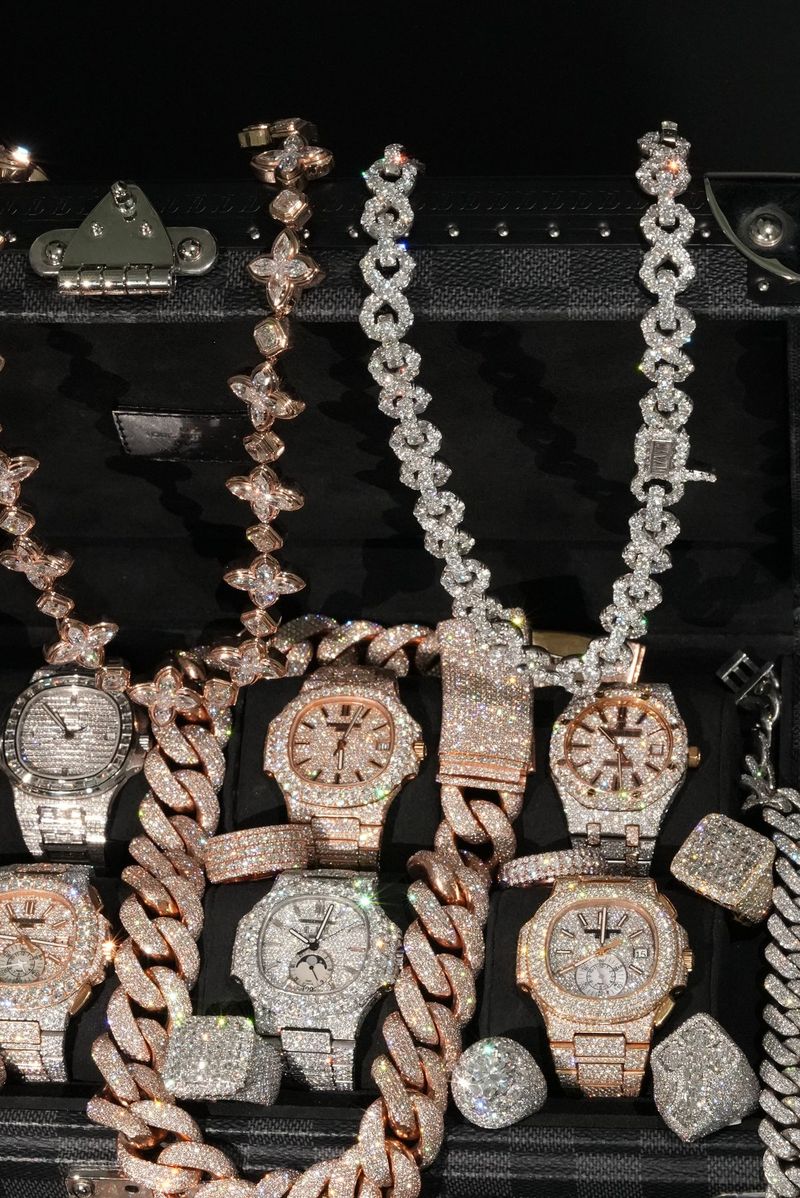 Flatlay of iced-out watches, Cuban link chains and pendants in a black case